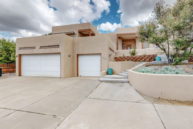 712 Navarra Way SE, Albuquerque, NM 87123 - pueblo-style home with concrete driveway, an attached garage, and stucco siding
