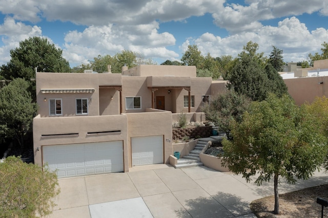 712 Navarra Way SE, Albuquerque, NM 87123 - pueblo revival-style home featuring an attached garage, driveway, stucco siding, and stairway