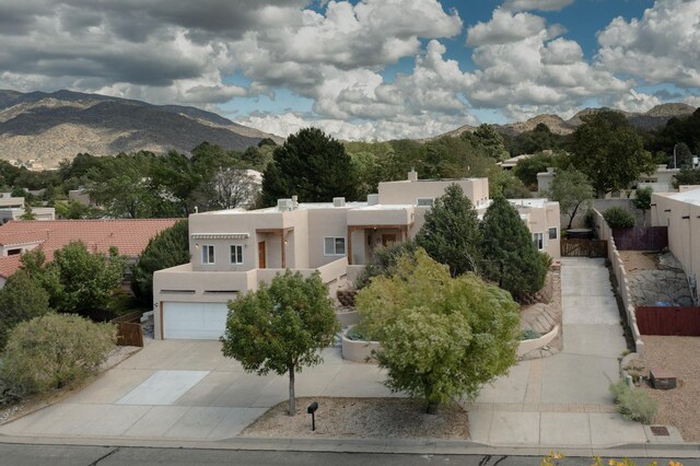 712 Navarra Way SE, Albuquerque, NM 87123 - adobe home with stucco siding, driveway, a mountain view, and a chimney