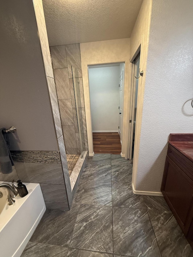 full bath with marble finish floor, baseboards, a textured ceiling, a bath, and a shower stall