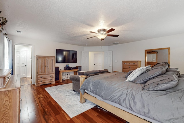 bedroom with ceiling fan, dark wood-style flooring, a textured ceiling, and visible vents