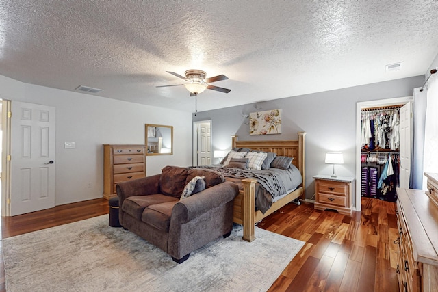 bedroom with a textured ceiling, visible vents, and wood finished floors