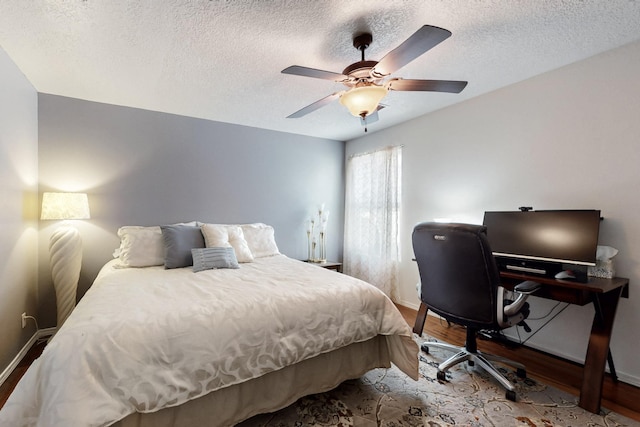 bedroom with a textured ceiling, baseboards, and wood finished floors