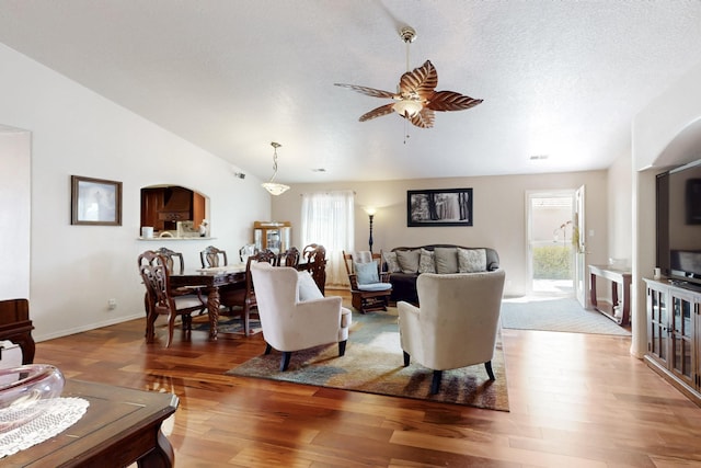 living area featuring ceiling fan, baseboards, wood finished floors, vaulted ceiling, and visible vents