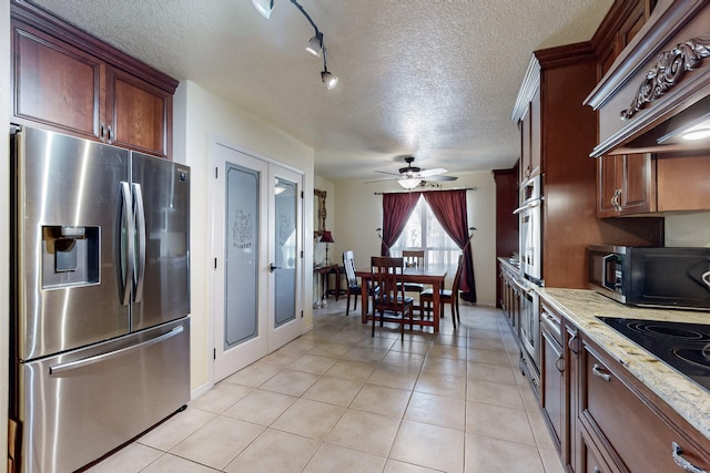 kitchen with ceiling fan, premium range hood, a textured ceiling, light tile patterned floors, and stainless steel appliances
