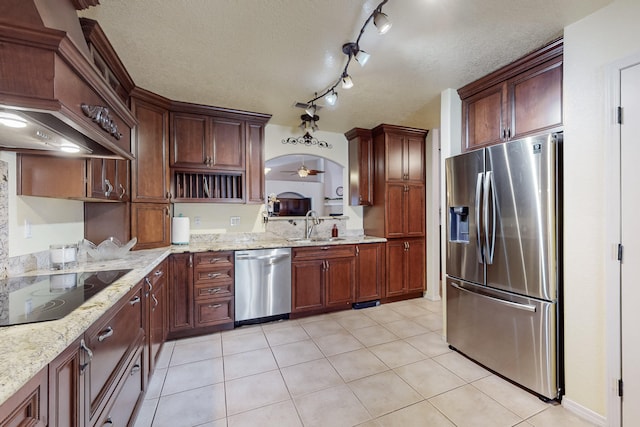 kitchen with a sink, a textured ceiling, appliances with stainless steel finishes, and light tile patterned floors
