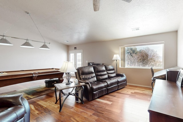 living room with baseboards, light wood finished floors, and a textured ceiling