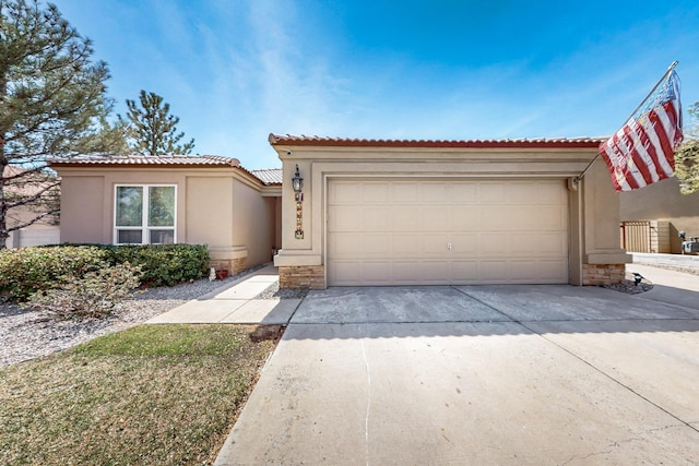mediterranean / spanish home featuring stone siding, stucco siding, a tiled roof, concrete driveway, and an attached garage
