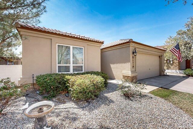 mediterranean / spanish home with an attached garage, stucco siding, a tile roof, and concrete driveway