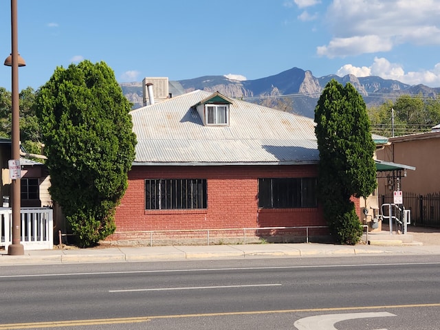 912 Camino Del Pueblo, Bernalillo, NM 87004 - view of front of home with brick siding, a mountain view, metal roof, and fence