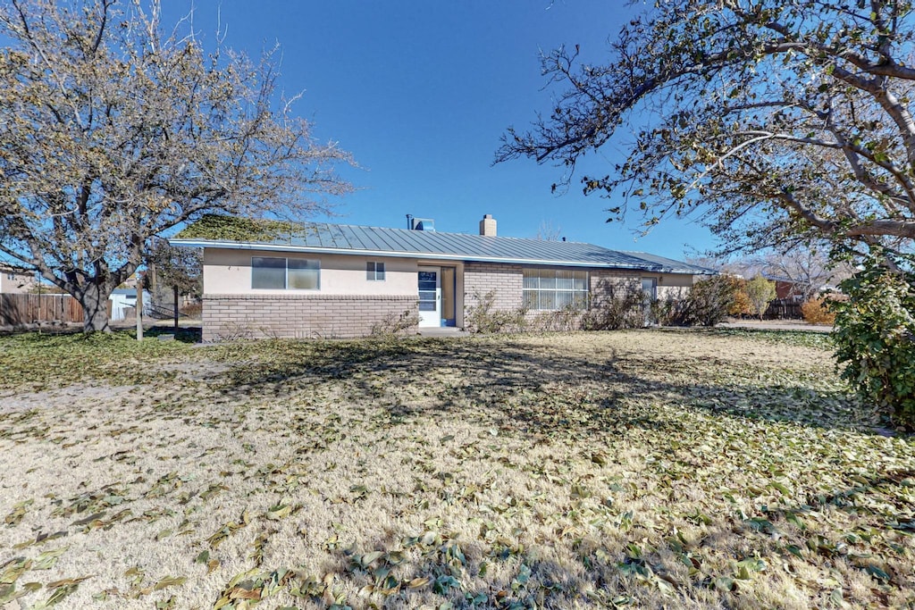 back of property with brick siding, fence, a chimney, metal roof, and a standing seam roof