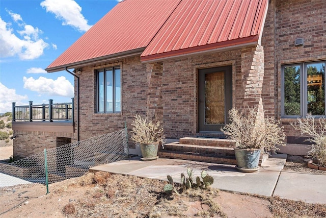 view of exterior entry with brick siding and metal roof
