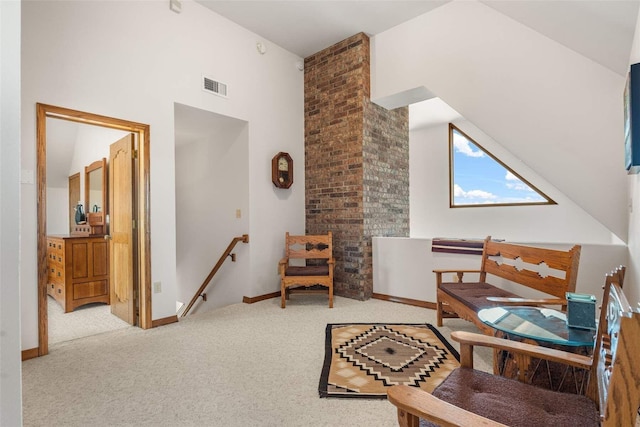 sitting room featuring a towering ceiling, visible vents, carpet floors, an upstairs landing, and baseboards