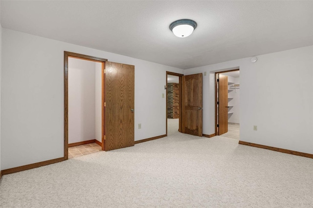 unfurnished bedroom with a walk in closet, baseboards, and carpet