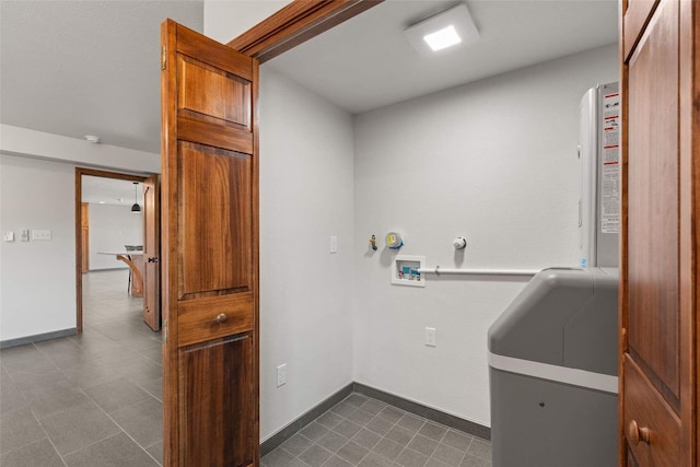 clothes washing area featuring dark tile patterned flooring, baseboards, and washer hookup