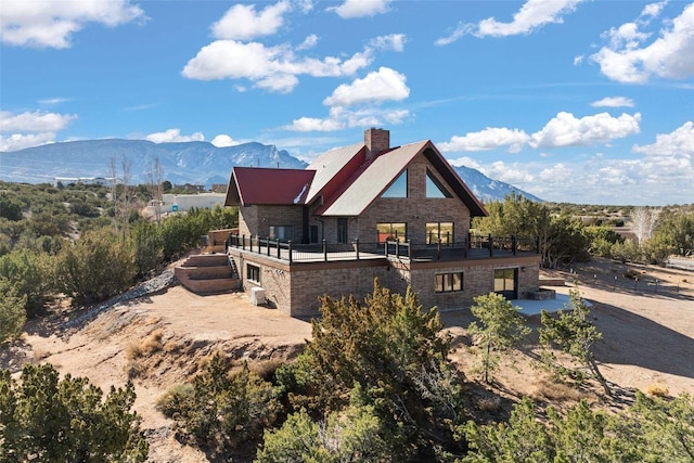 back of property with a mountain view and stone siding