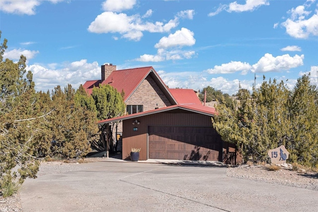 view of side of home featuring metal roof, a garage, and a chimney