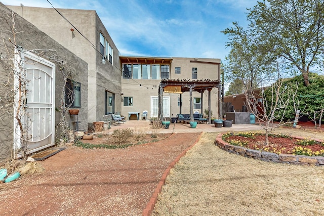 rear view of house with a pergola, stucco siding, and a patio area