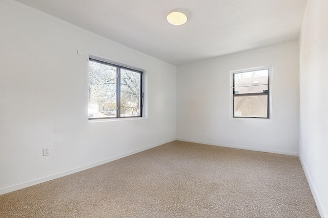 carpeted empty room featuring baseboards