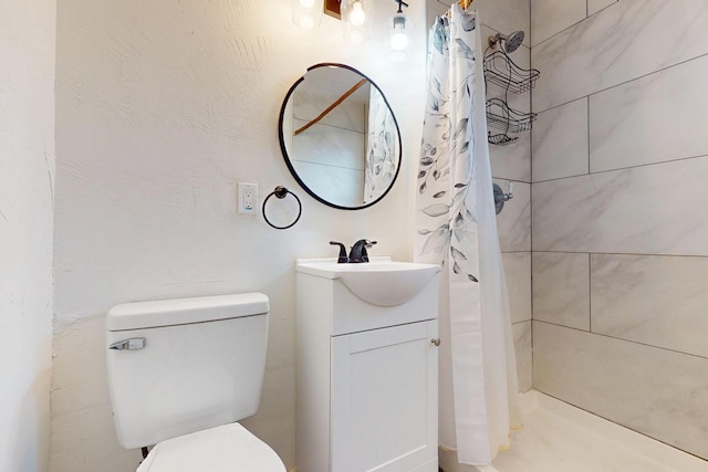 full bath with toilet, tiled shower, and vanity