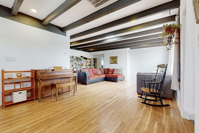 living area with visible vents, beamed ceiling, and wood finished floors
