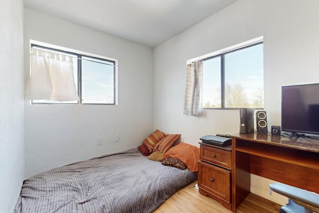 bedroom with multiple windows and light wood-style floors