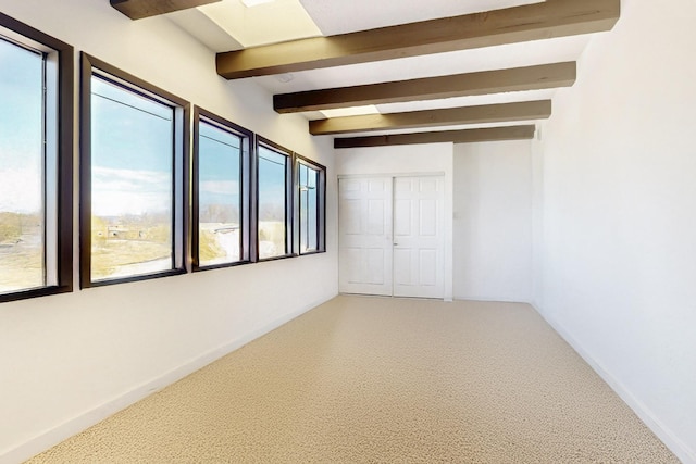 spare room with beamed ceiling and baseboards