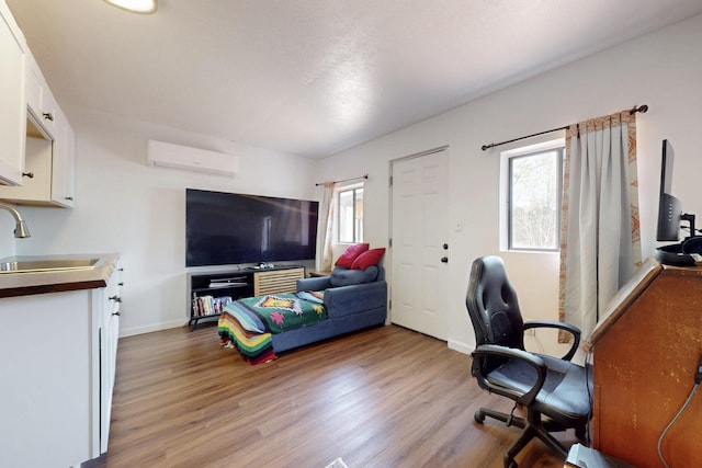 interior space with a sink, baseboards, a wall mounted AC, and wood finished floors