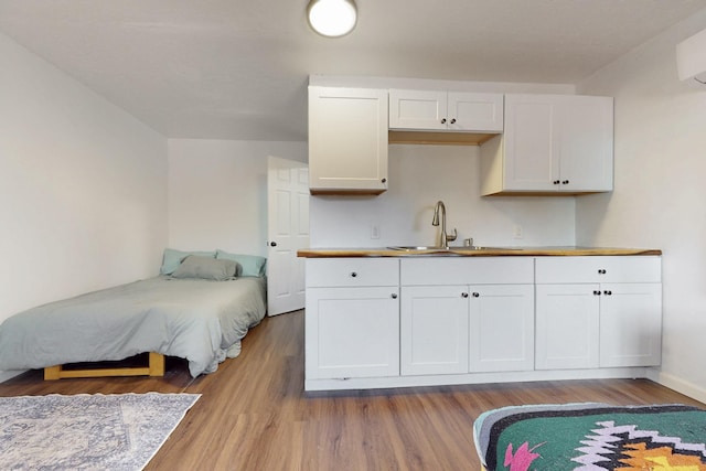 bedroom featuring baseboards, light wood-type flooring, and a sink