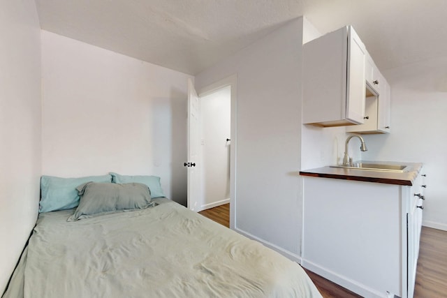 bedroom with a sink, baseboards, and dark wood finished floors