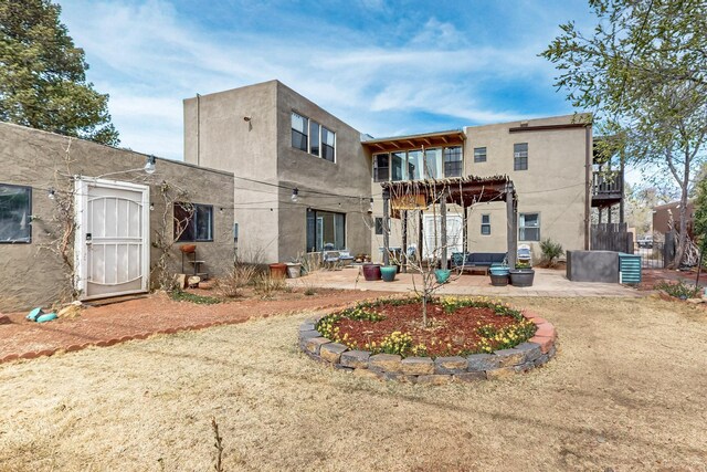 back of property featuring a pergola, a patio, and stucco siding