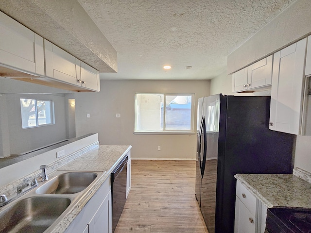 kitchen with light wood-style floors, white cabinets, black dishwasher, a sink, and baseboards