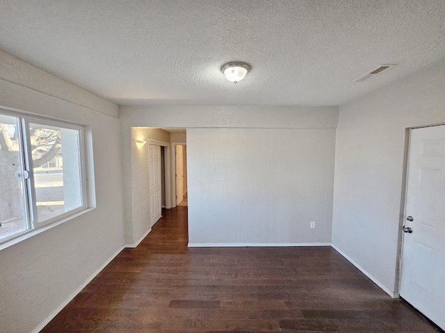 empty room featuring visible vents, baseboards, and wood finished floors