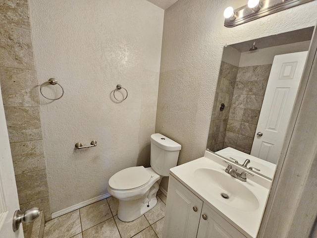 bathroom featuring vanity, tile patterned flooring, toilet, a textured wall, and baseboards