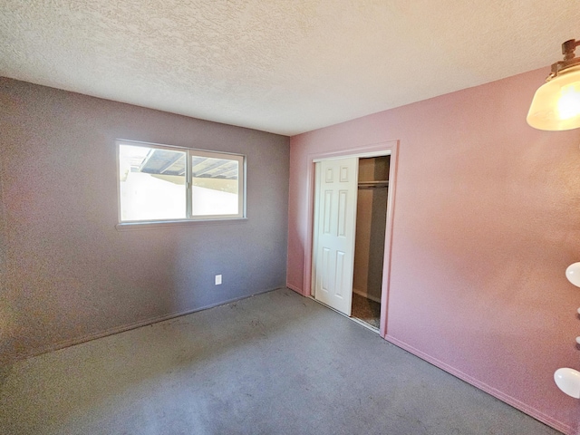 unfurnished bedroom with baseboards, carpet flooring, a closet, and a textured ceiling