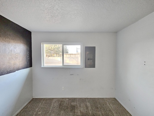 carpeted spare room with electric panel, a textured ceiling, and baseboards