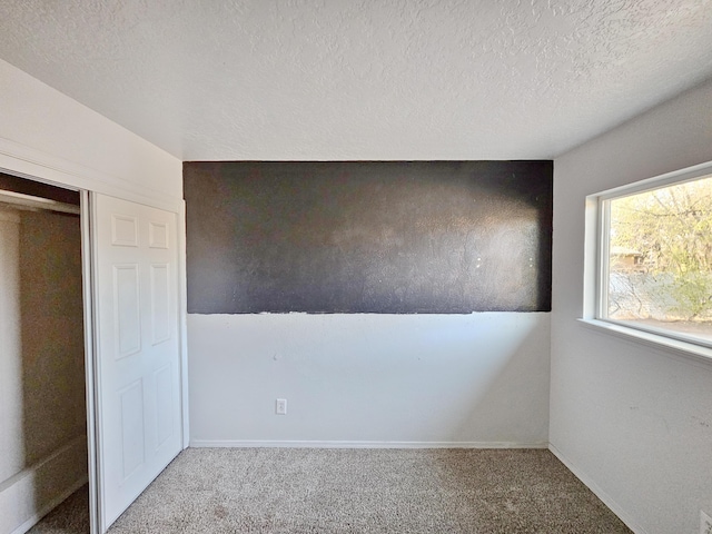unfurnished bedroom featuring baseboards, carpet flooring, and a textured ceiling