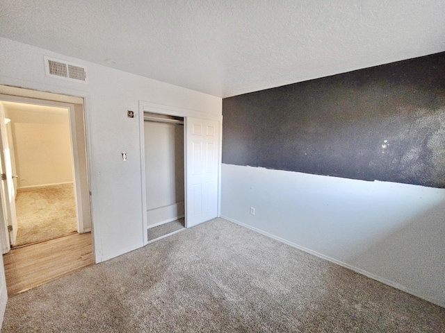 unfurnished bedroom featuring carpet floors, a closet, visible vents, and a textured ceiling