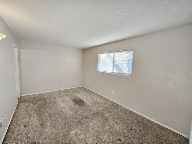 carpeted spare room with baseboards and a textured ceiling