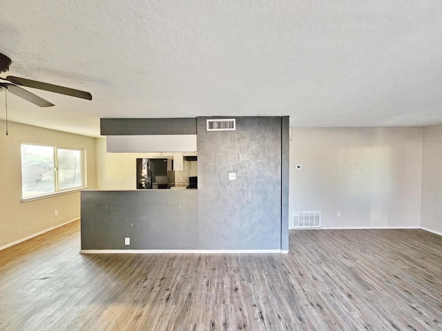 empty room featuring visible vents, a ceiling fan, and wood finished floors