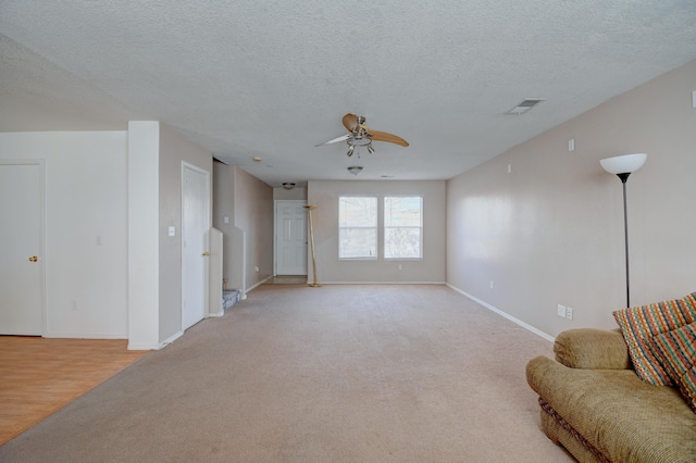 5750 Quay St, Rio Rancho, NM 87144 - living room featuring a ceiling fan, baseboards, visible vents, a textured ceiling, and light colored carpet