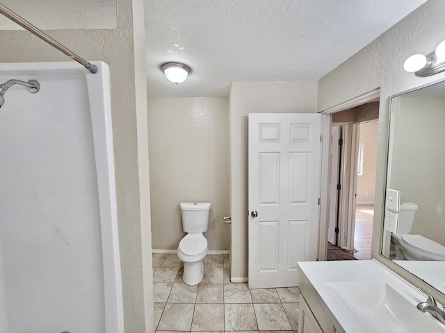 bathroom with toilet, a textured wall, vanity, and a textured ceiling