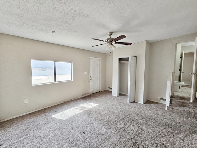 unfurnished bedroom with a ceiling fan, a textured ceiling, visible vents, and carpet
