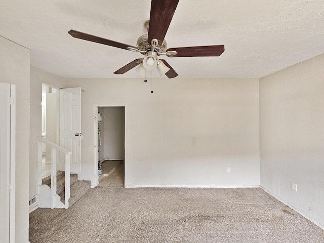 interior space featuring ceiling fan, a textured ceiling, baseboards, and light carpet