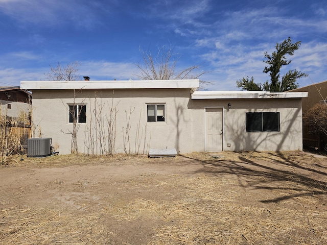 back of property with central AC unit and stucco siding