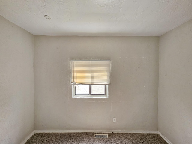 carpeted spare room featuring baseboards and visible vents