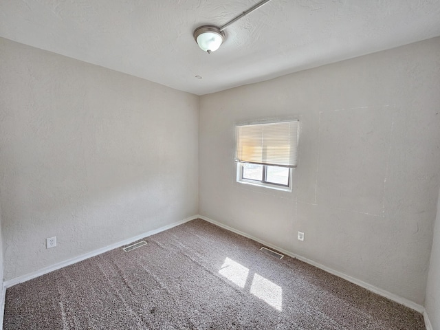 unfurnished room with baseboards, visible vents, and carpet