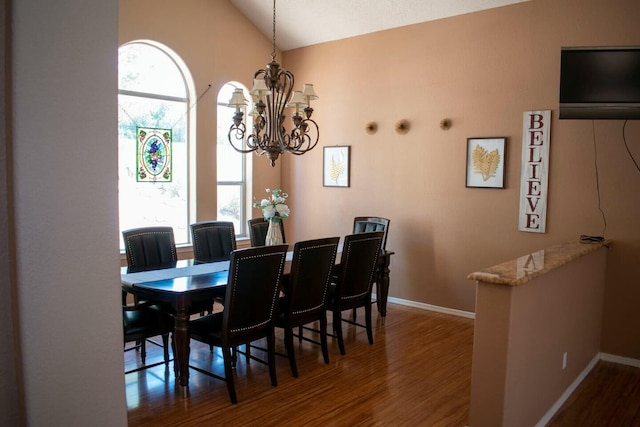 dining area featuring baseboards, lofted ceiling, a chandelier, and wood finished floors