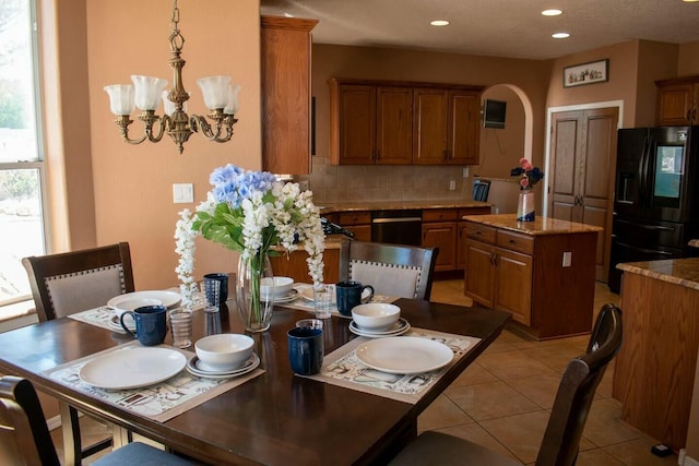 kitchen featuring an inviting chandelier, backsplash, dishwasher, black fridge with ice dispenser, and brown cabinetry