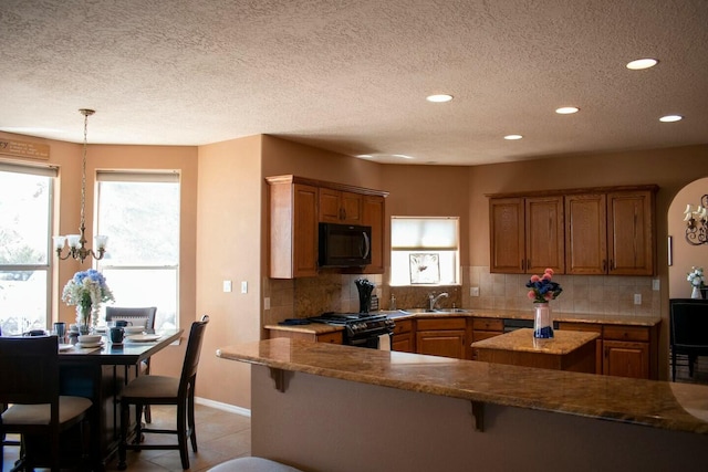 kitchen featuring black appliances, decorative backsplash, a sink, and a kitchen island